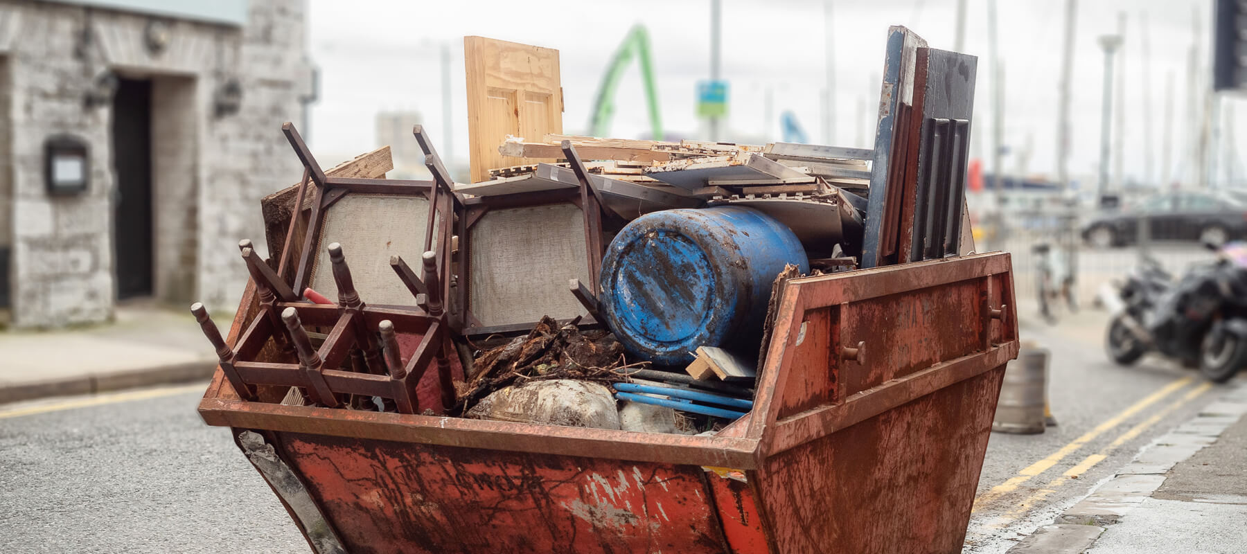 Old Rusty Dumpster Skip In A Street Fool Of Rubbish And Old Furn